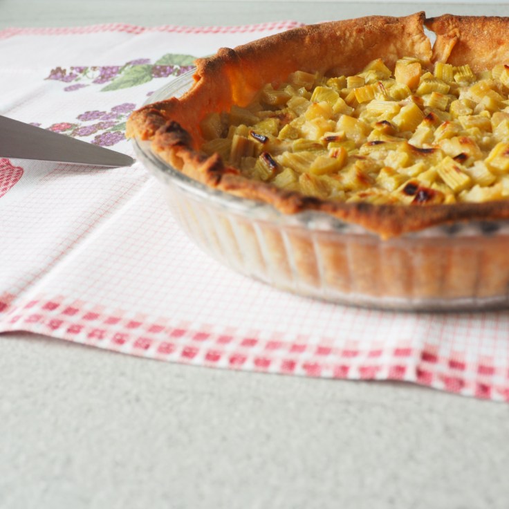 Tarte à la rhubarbe dans son plat sur une nappe quadrillée.