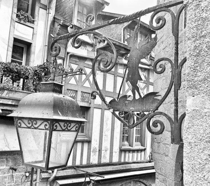 Petit oiseau sur un lampadaire lanterne en fer forgé représentant saint Michel terrassant le dragon