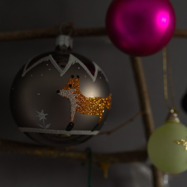 Gros plan sur une boule de Noël décorée d'un renard en paillettes orange.