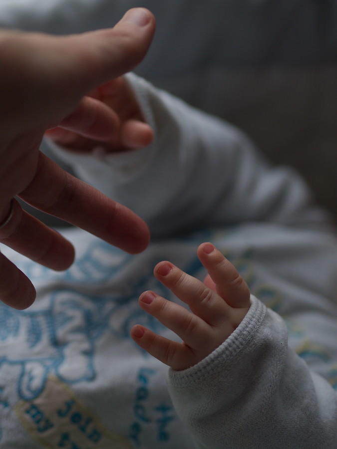 Mains de bébé tendues vers une main adulte.